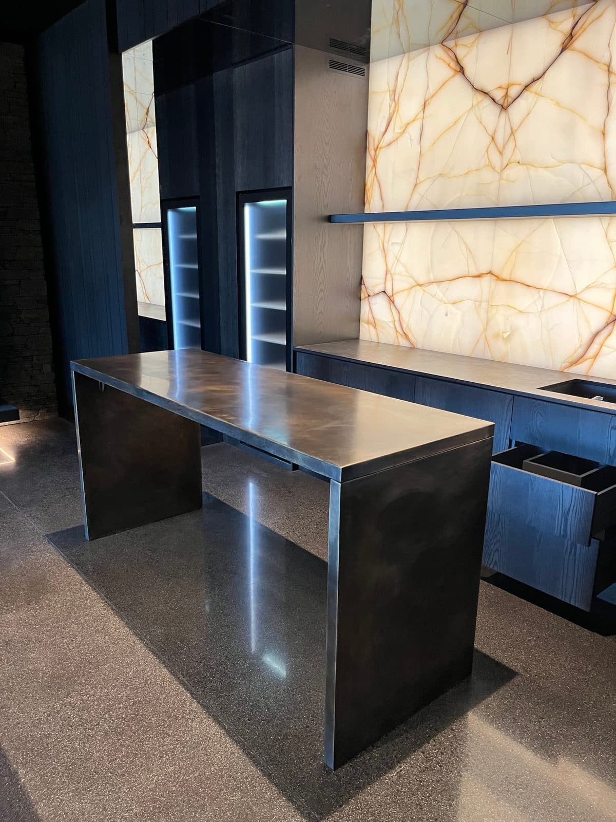 Patinated bronze bar in front of a backlit onyx wall