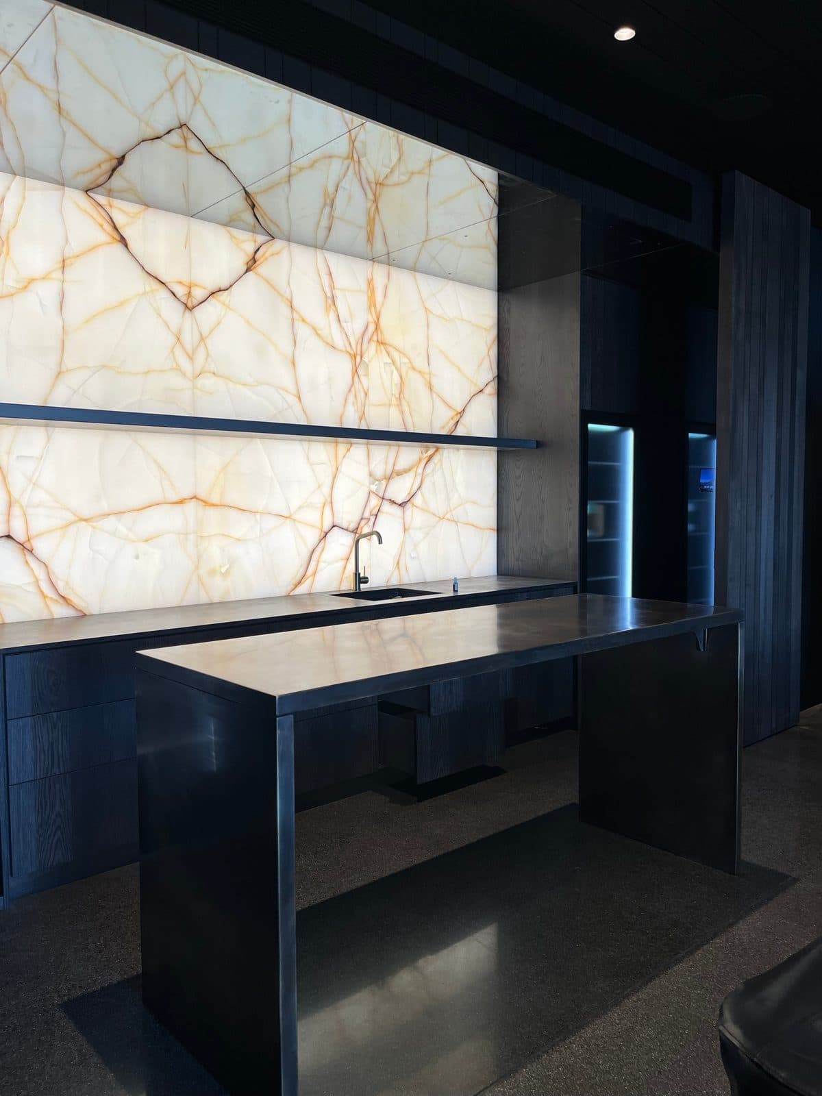 The bronze bar and bench under the onyx wall, seen from the room