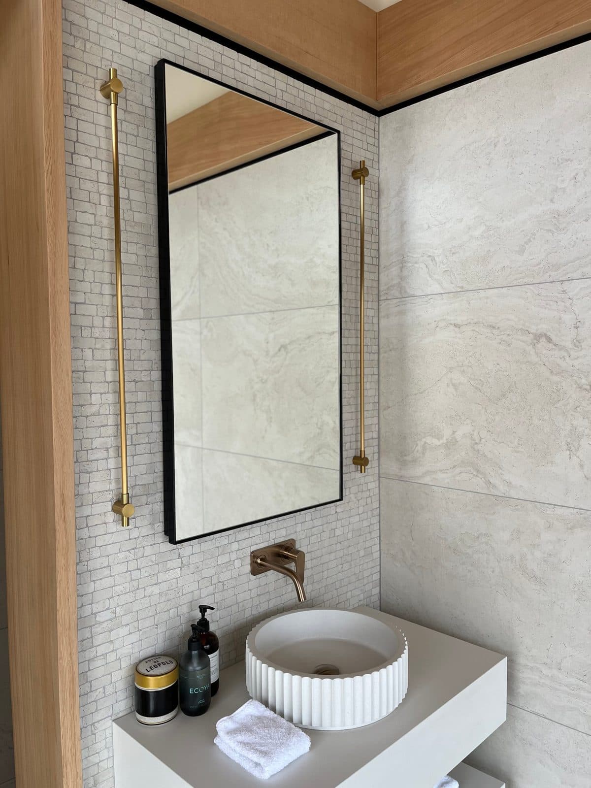 Black mirror and brass rails on a mosaic wall