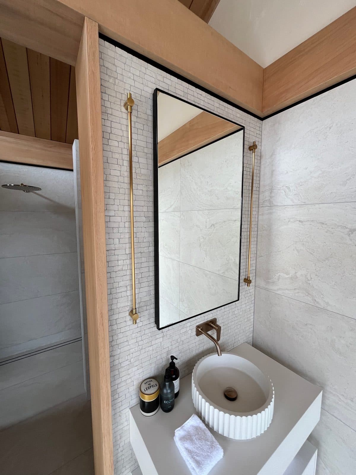 Black mirror and brass rails beside the shower